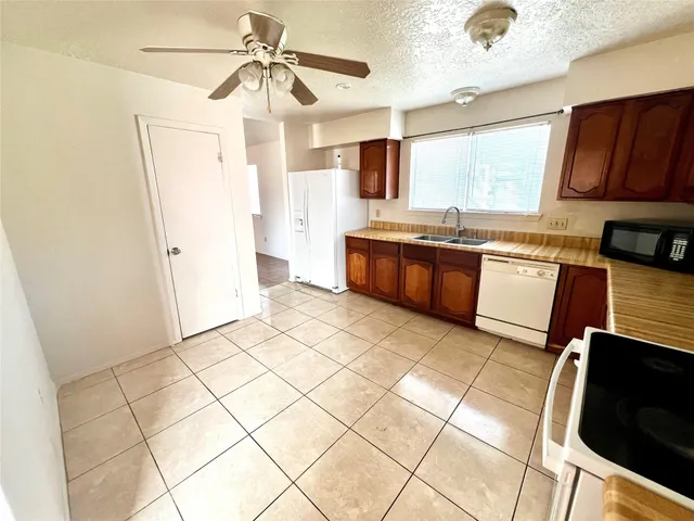 a large kitchen with granite countertop white cabinets and stainless steel appliances