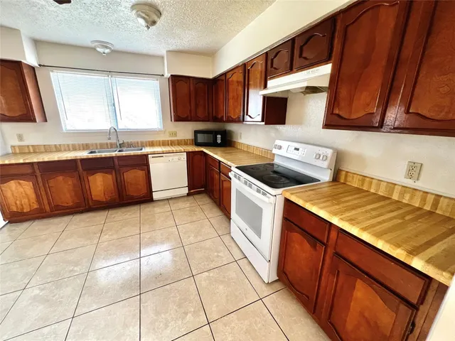 a kitchen with stainless steel appliances a stove a sink a microwave a refrigerator and cabinets