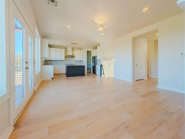 an empty room with wooden floor fireplace and windows