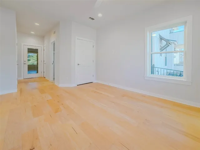 a view of a hallway with wooden floor and a bathroom
