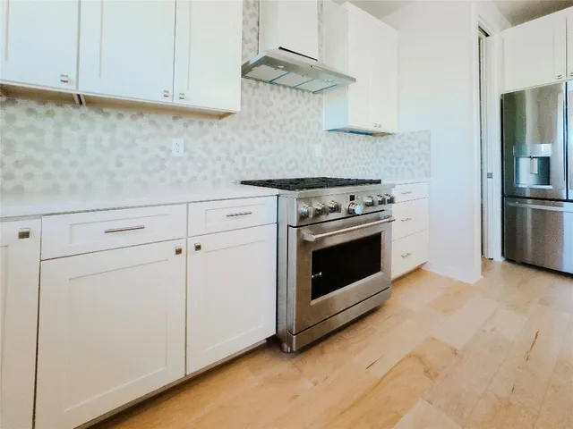 a kitchen with granite countertop white cabinets and white stainless steel appliances