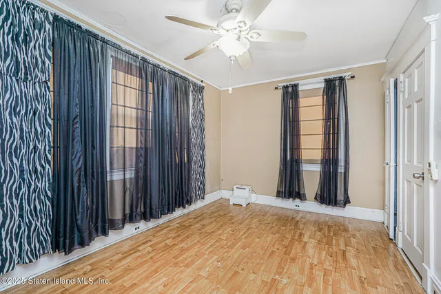 a view of a bedroom with wooden floor and a ceiling fan