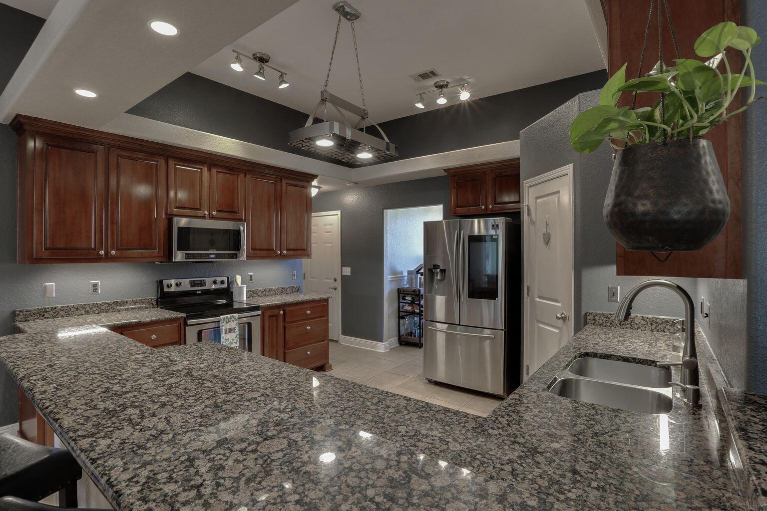 136 Leonine Hollow Crestview, FL 32536 - Photo 12 of 27 a kitchen with stainless steel appliances granite countertop a refrigerator a stove a sink a microwave oven with a dining table and chairs