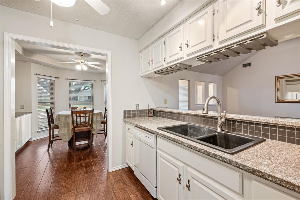 6605 Bluebonnet Drive Rowlett, TX 75089 - Photo 9 of 25 a kitchen with stainless steel appliances granite countertop a sink dishwasher and white cabinets with wooden floor