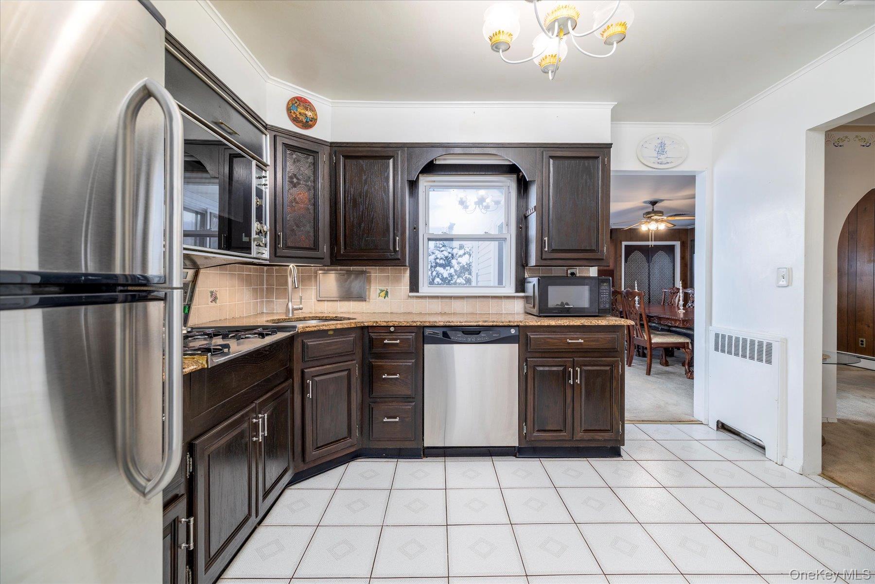 2934 Kinloch Road Wantagh, NY 11793 - Photo 11 of 30 Kitchen with dark brown cabinetry, stainless steel appliances, radiator heating unit