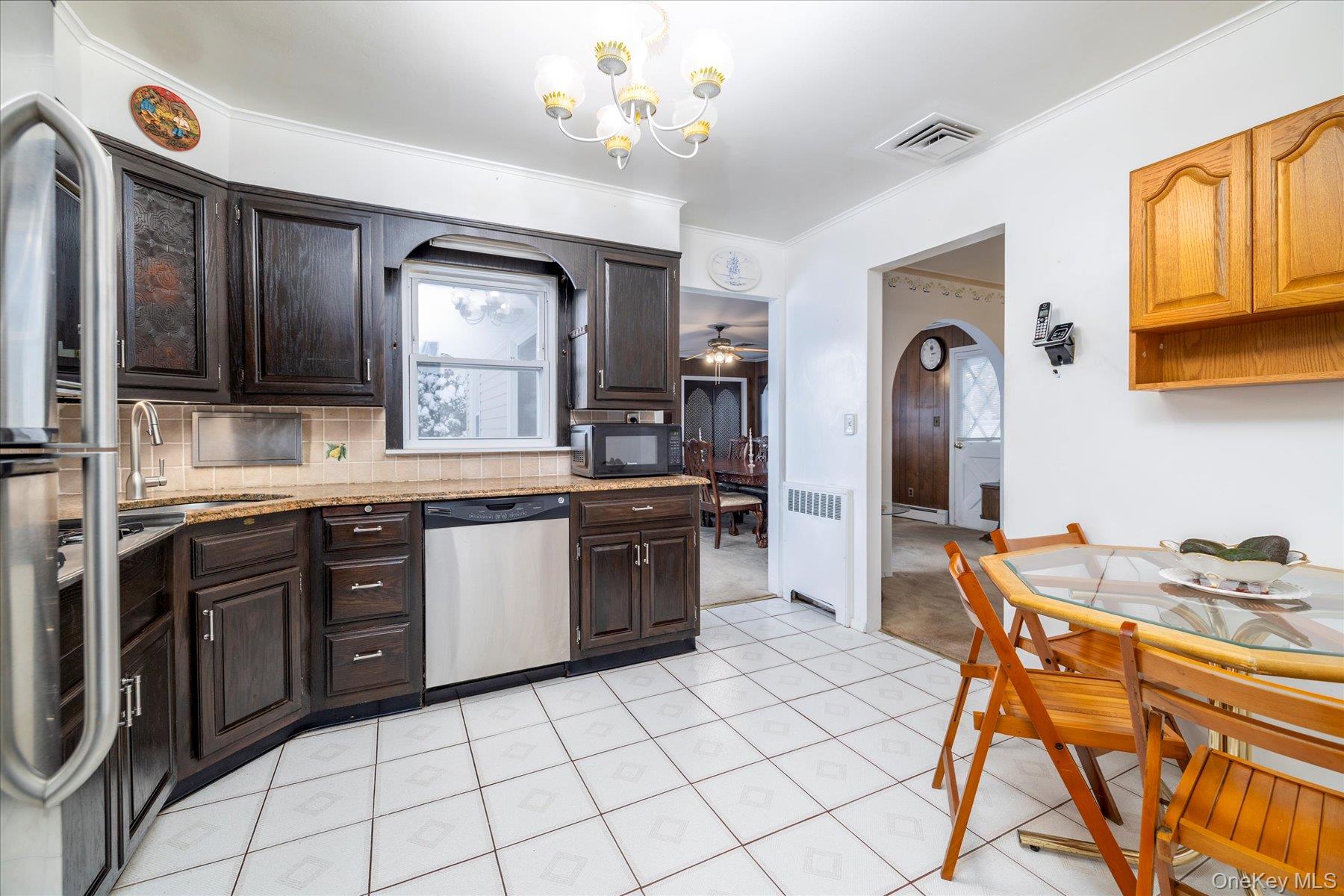2934 Kinloch Road Wantagh, NY 11793 - Photo 12 of 30 Kitchen with arched walkways, stainless steel appliances, dark brown cabinetry, and backsplash