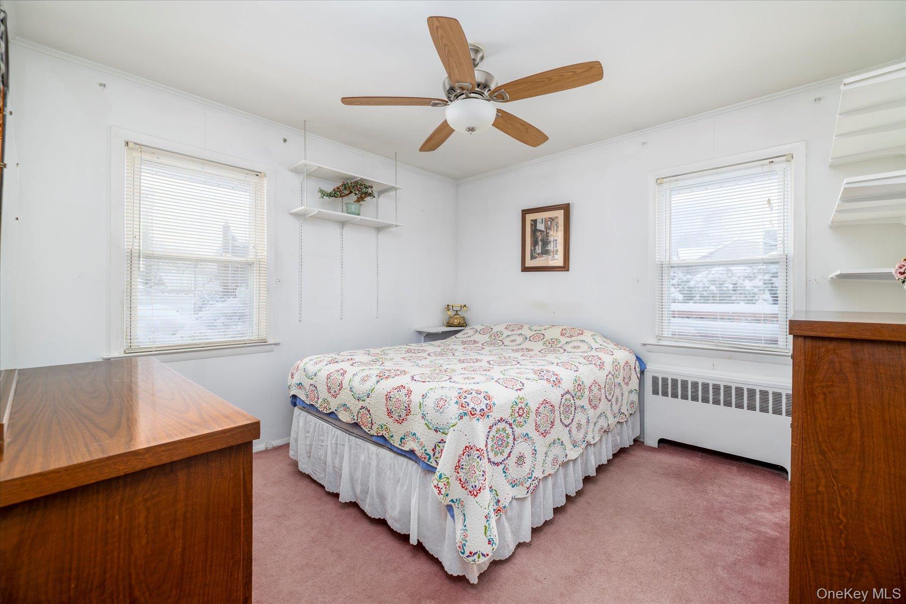 2934 Kinloch Road Wantagh, NY 11793 - Photo 14 of 30 Bedroom with radiator heating unit, ornamental molding, multiple windows, light colored carpet, and ceiling fan