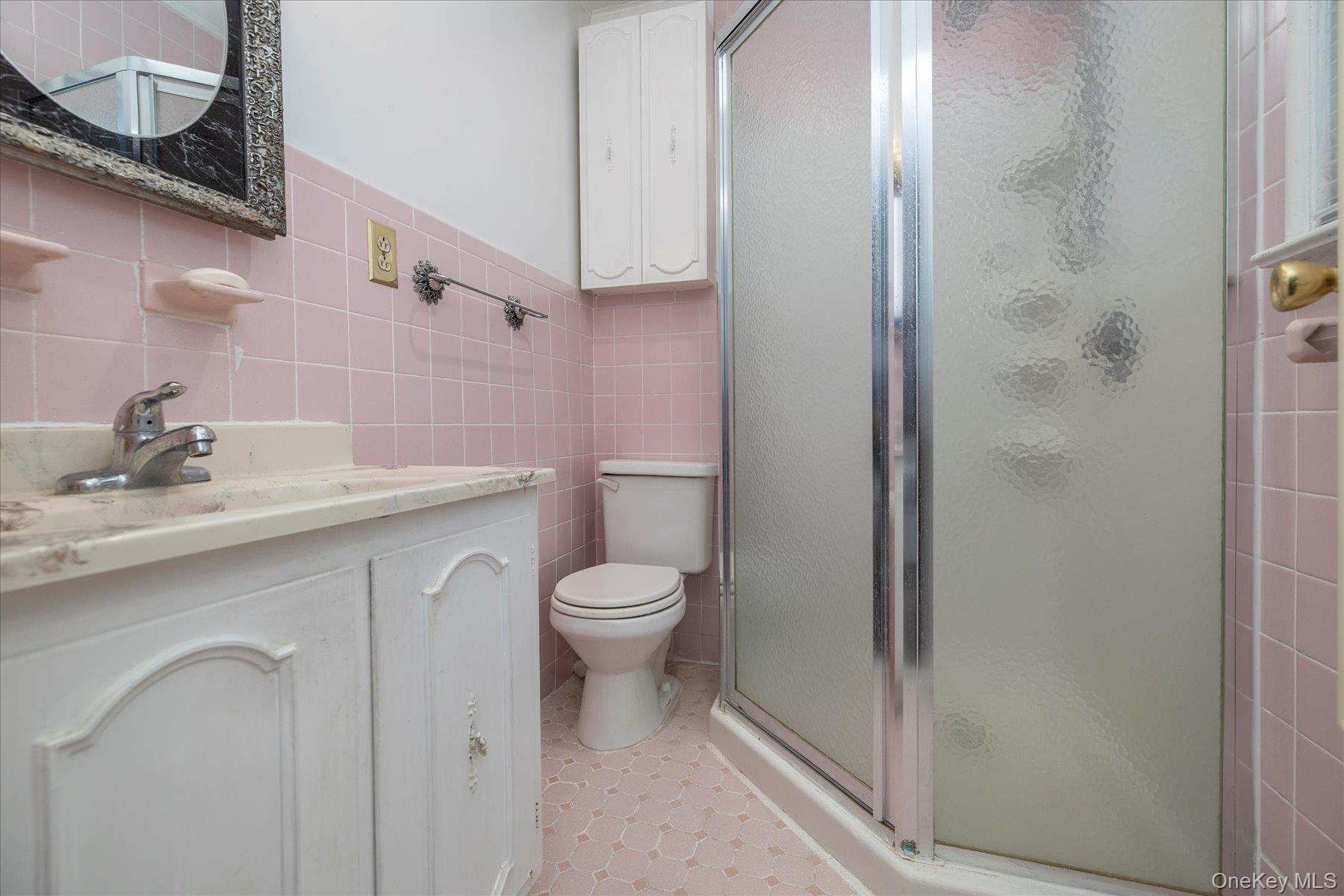 2934 Kinloch Road Wantagh, NY 11793 - Photo 17 of 30 Bathroom with tile walls, a shower stall, vanity, wainscoting, and light tile patterned floors