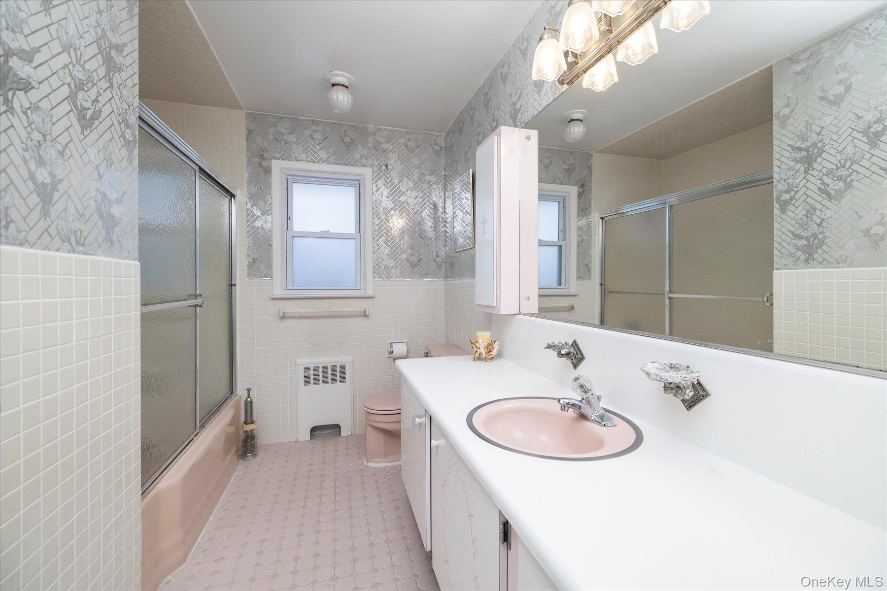 2934 Kinloch Road Wantagh, NY 11793 - Photo 18 of 30 Bathroom with tile walls, vanity, wallpapered walls, radiator heating unit, and bath / shower combo with glass door