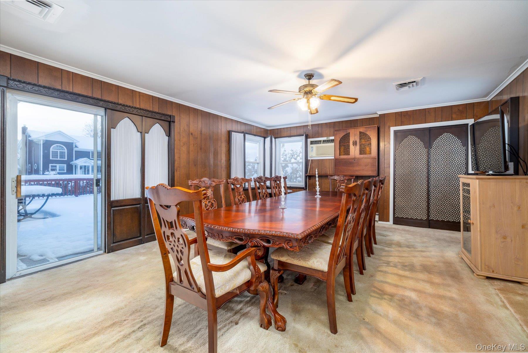 2934 Kinloch Road Wantagh, NY 11793 - Photo 8 of 30 Dining area with light colored carpet, wooden walls, ornamental molding, and ceiling fan