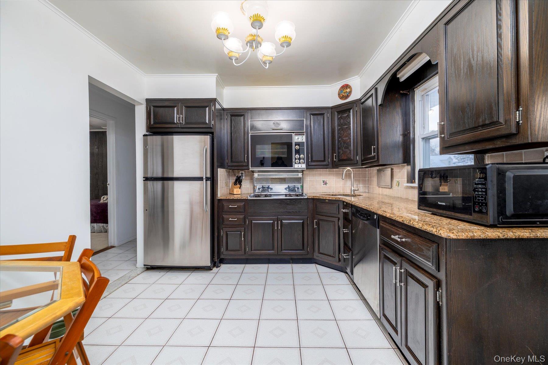2934 Kinloch Road Wantagh, NY 11793 - Photo 10 of 30 Kitchen with stainless steel appliances, dark brown cabinetry, tasteful backsplash, a chandelier