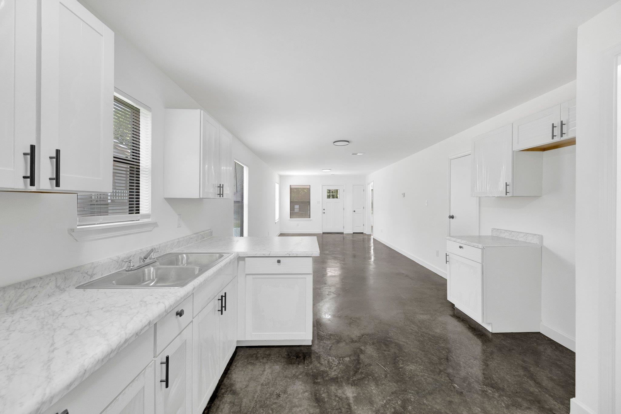 653 Gilleas Road Memphis, TN 38109 - Photo 16 of 24 a large white kitchen with white cabinets and wooden floor