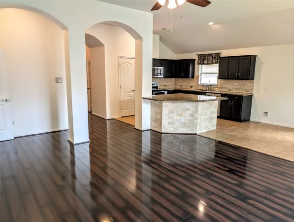 a view of kitchen with stainless steel appliances wooden floor and living room view