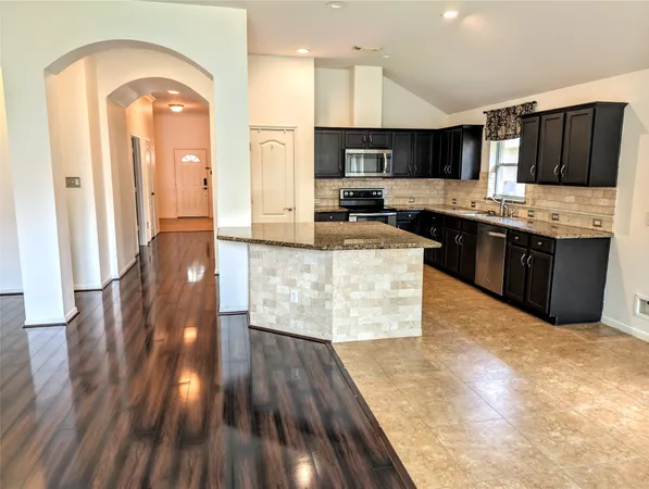 a kitchen with granite countertop a sink stove and cabinets