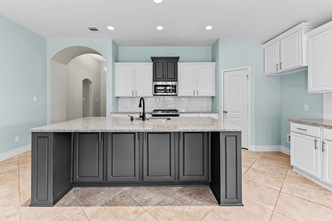 217 Serrano Street Georgetown, TX 78628 - Photo 12 of 27 a kitchen with kitchen island a sink stainless steel appliances and cabinets