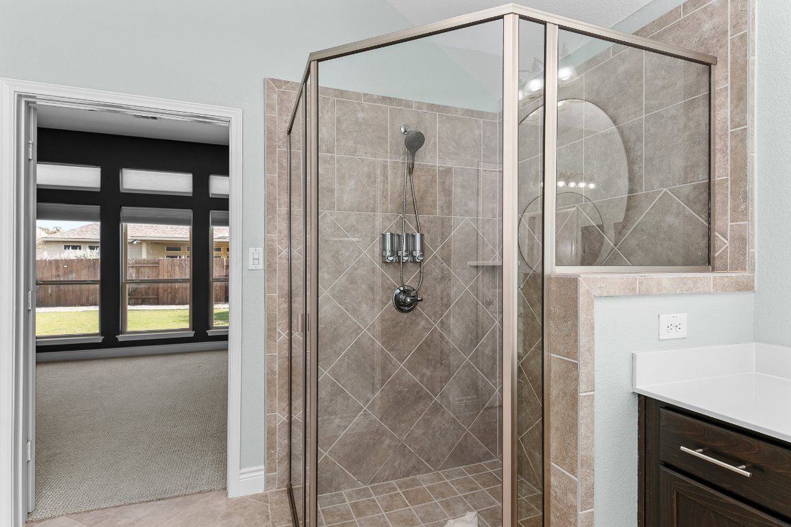 217 Serrano Street Georgetown, TX 78628 - Photo 25 of 27 a bathroom with a glass shower door and a mirror