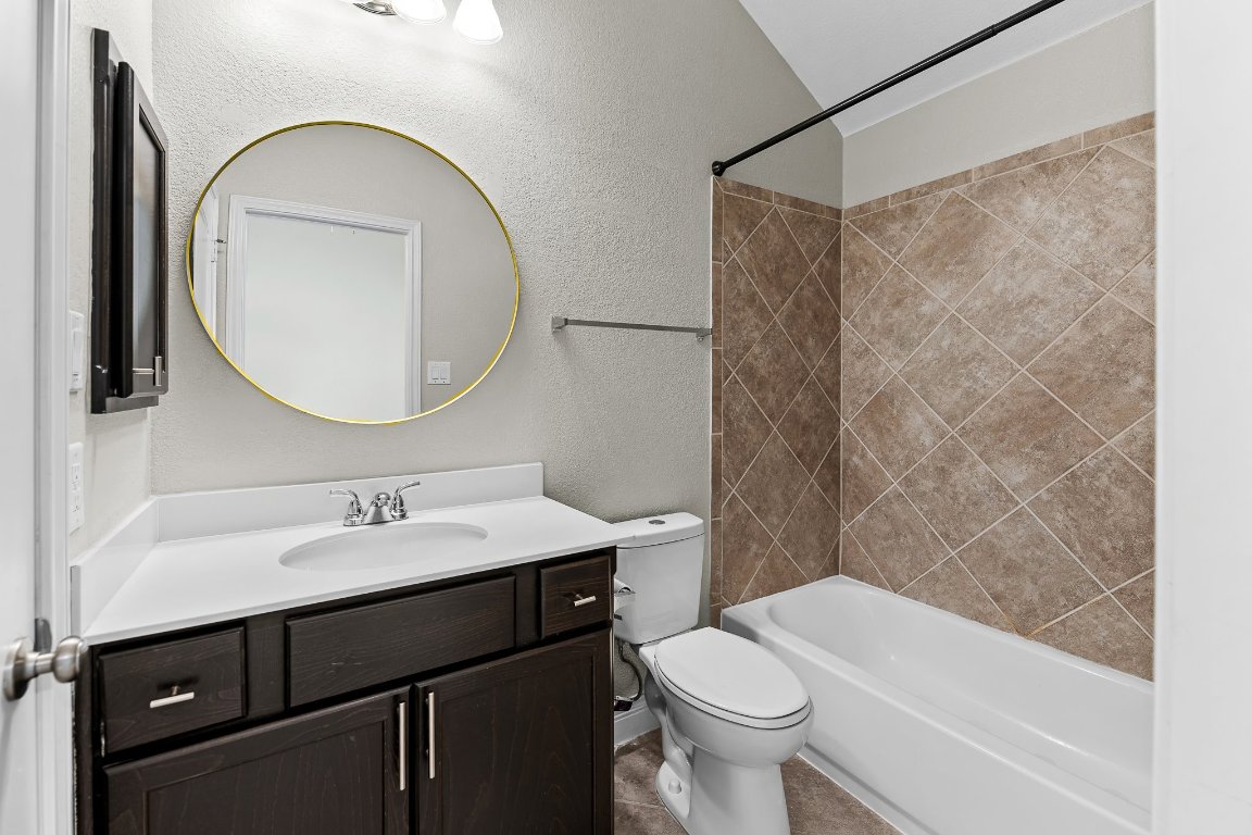 217 Serrano Street Georgetown, TX 78628 - Photo 7 of 27 a bathroom with a sink a toilet and a mirror