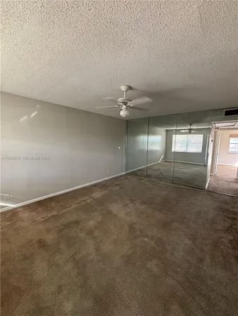 an empty room with chandelier and fan