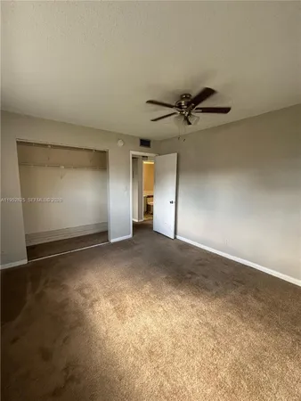 an empty room with a ceiling fan and a window