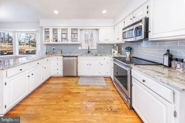 a large kitchen with stainless steel appliances granite countertop a stove sink and cabinets