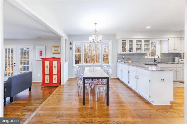 a large white kitchen with stainless steel appliances granite countertop a stove and a dining table with white cabinets