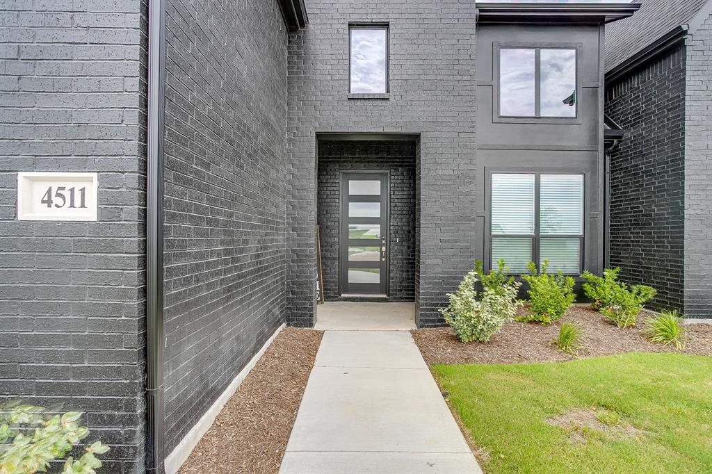 4511 Matador Rnch Road Waxahachie, TX 75165 - Photo 4 of 36 Contemporary brick exterior with a prominent entrance, modern front door featuring frosted glass panels, and well-maintained landscaping