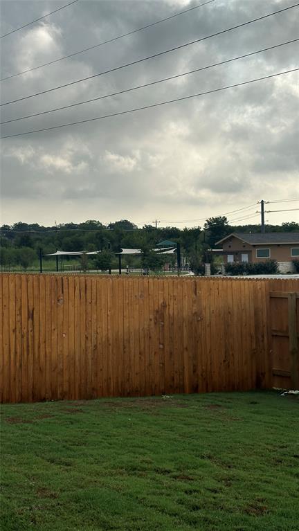 204 Inks Lane Kyle, TX 78640 - Photo 23 of 25 A robust wooden fence encloses a verdant lawn, backing onto a park with shaded areas.