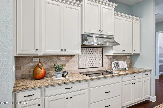 a kitchen with a stove center island wooden floor and living room view