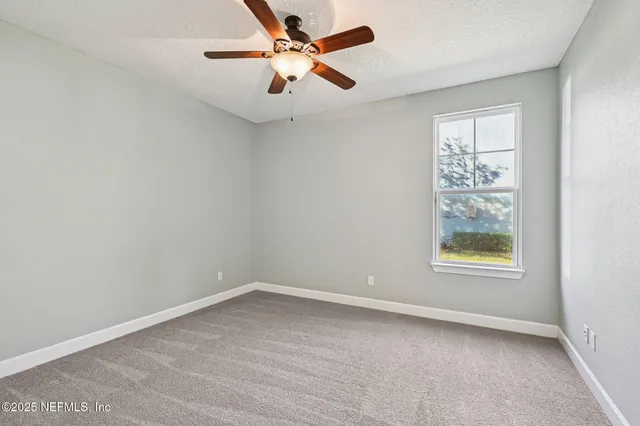 an empty room with windows and chandelier fan