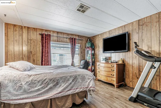 a bedroom with a bed a flat screen tv and dresser