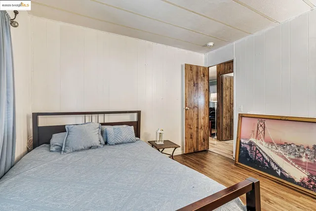 a bedroom with a bed a dresser and wooden floor