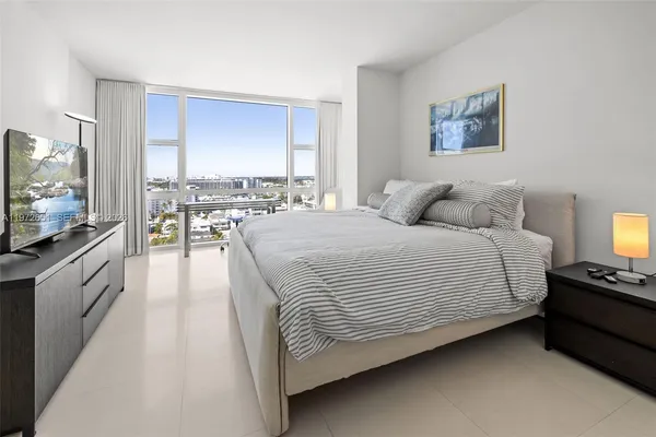 a spacious bedroom with a bed and a flat screen tv