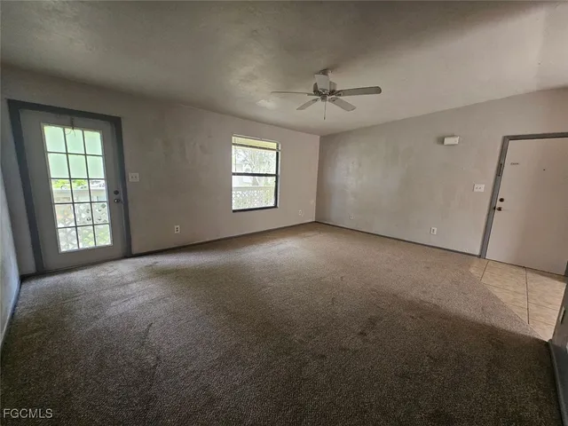 an empty room with windows and ceiling fan