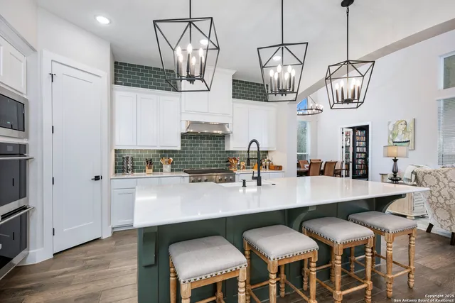 a kitchen with stainless steel appliances granite countertop a sink a stove a dining table and chairs