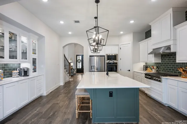 a large kitchen with stainless steel appliances a stove center island a oven a dining table and chairs