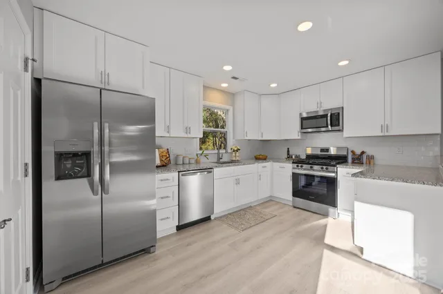 a kitchen with stainless steel appliances granite countertop a refrigerator a sink and a stove