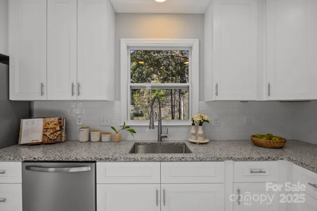 a kitchen with granite countertop white cabinets and a window