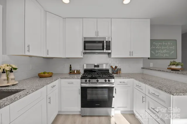 a kitchen with granite countertop white cabinets and stainless steel appliances