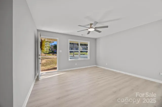 an empty room with windows and ceiling fan