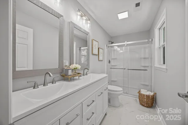 a bathroom with a double vanity sink mirror and toilet