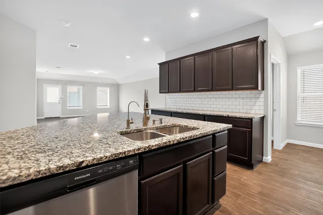 a kitchen with granite countertop kitchen island a sink appliances and wooden cabinets