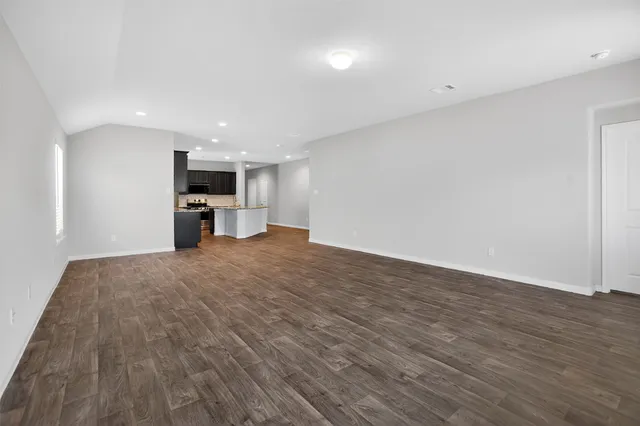 a view of empty room with wooden floor and a window