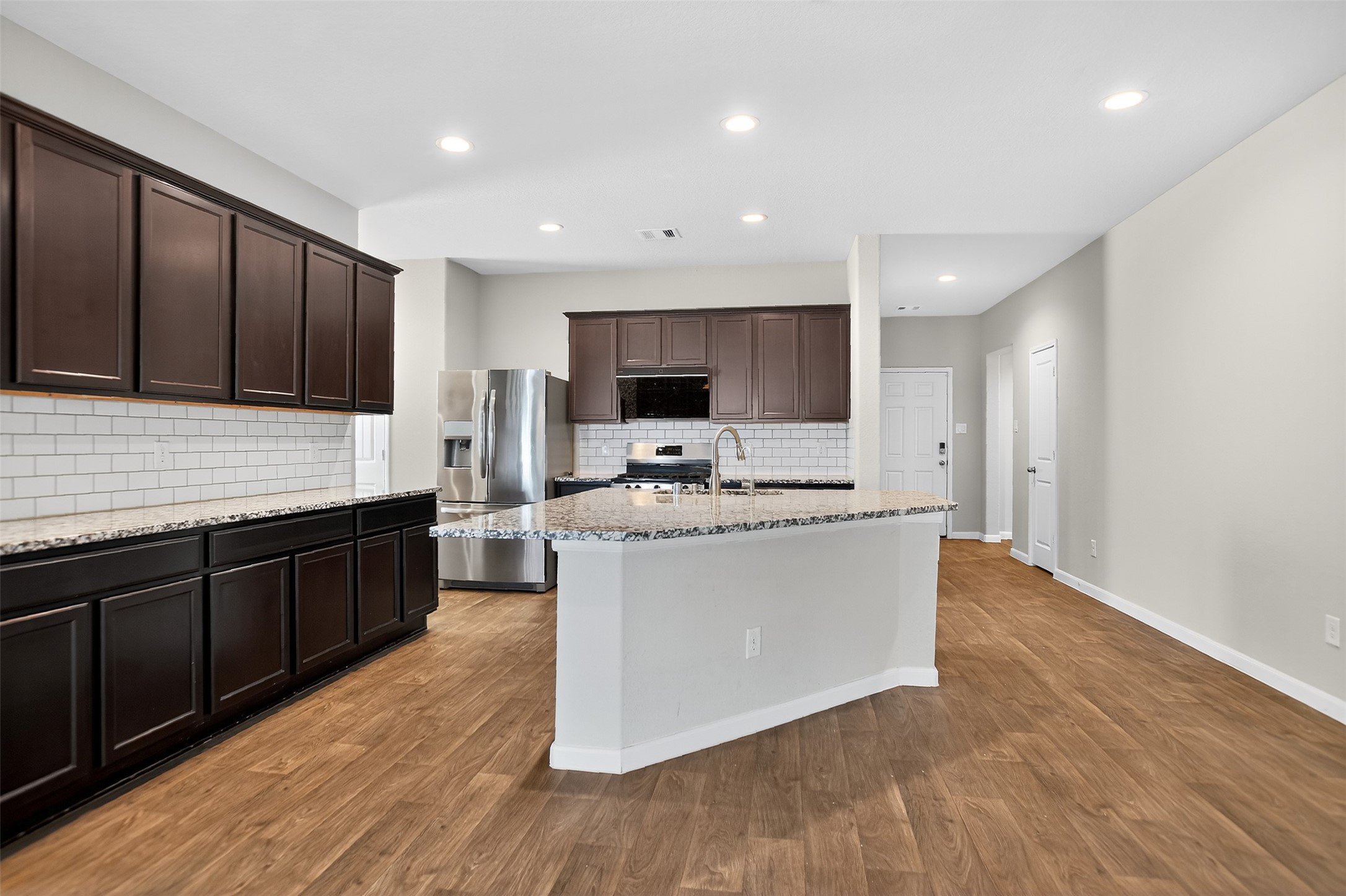 3310 Sumac Drive Katy, TX 77494 - Photo 31 of 45 a large kitchen with stainless steel appliances kitchen island granite countertop a stove a sink dishwasher a microwave oven and a refrigerator with wooden floor