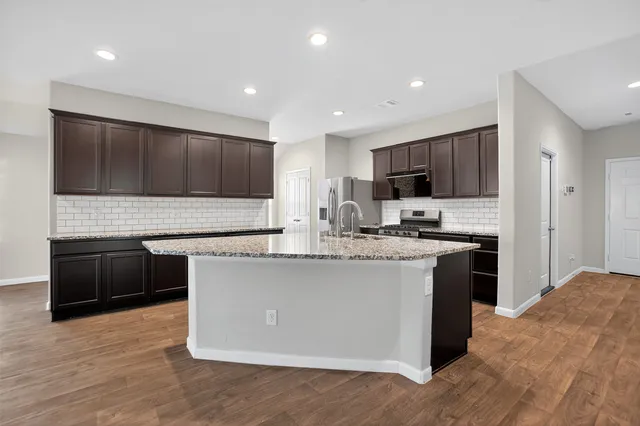 a kitchen with stainless steel appliances granite countertop a stove top oven a sink and a microwave