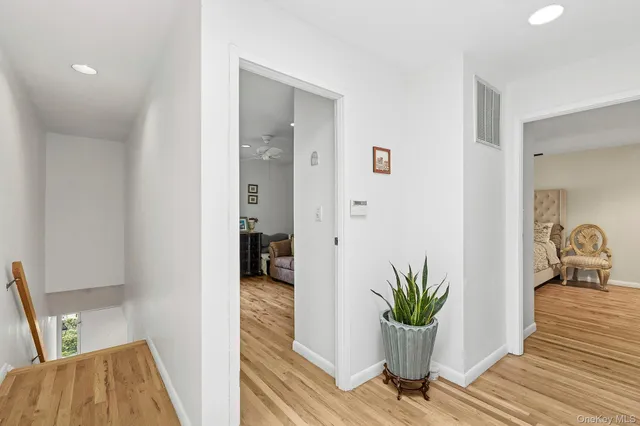 a view of a hallway with wooden floor and a bathroom