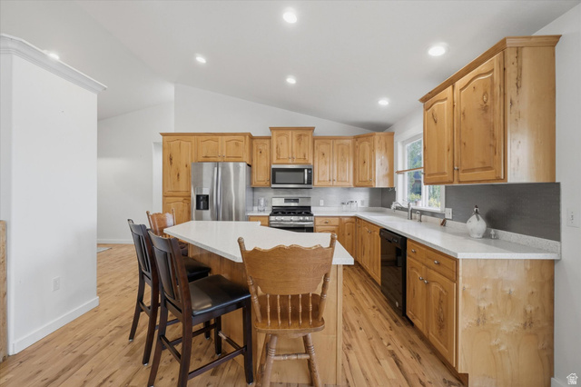 791 East Saddle Road Grantsville, UT 84029 - Photo 8 of 46 Kitchen featuring wood-finish cabinetry, stainless steel appliances, a center island with seating, white countertops, and wood-finish flooring