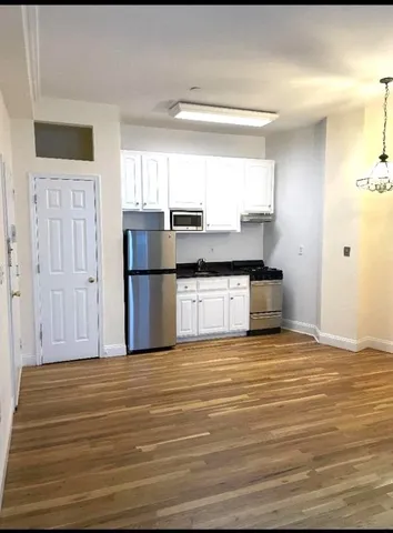 a view of a kitchen with wooden floor and electronic appliances