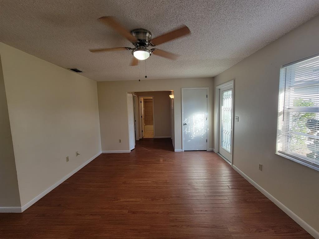 23358 Racine Avenue Punta Gorda, FL 33980 - Photo 10 of 28 an empty room with wooden floor chandelier fan and windows