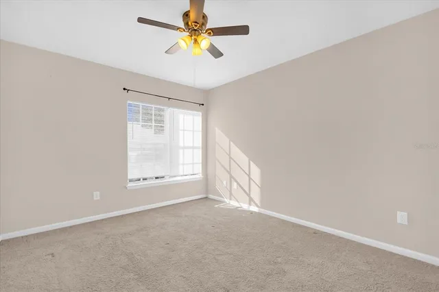 an empty room with a window and a fan