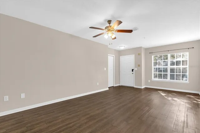 a view of an empty room with a window and wooden floor
